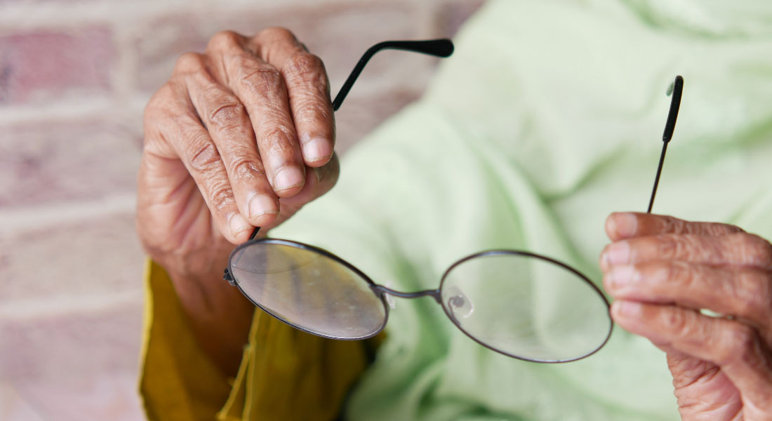 Old hands holding a pair of glasses