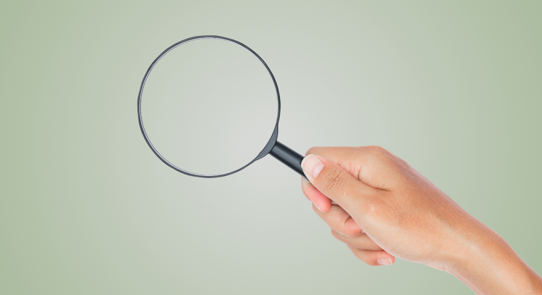 Magnifying glass in hand on green background